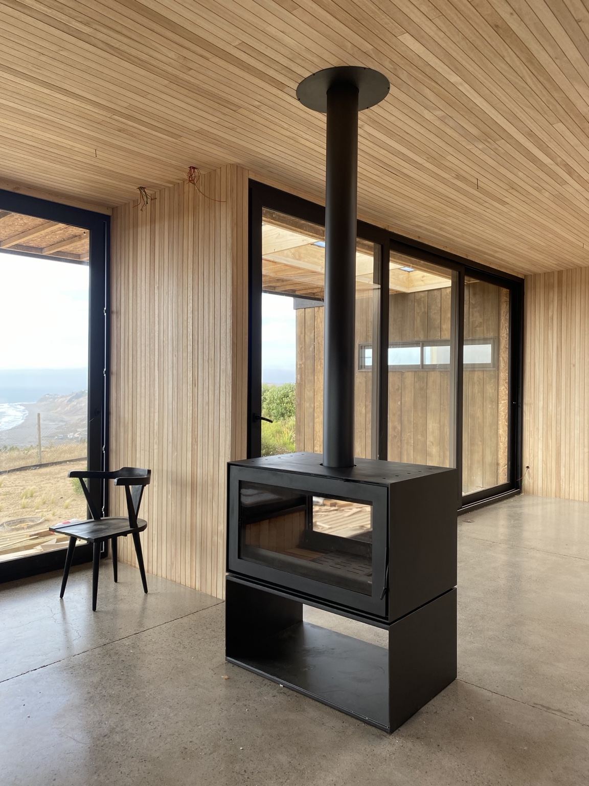Chimenea de doble vista con leñero inferior instalada en vivienda con vista al mar