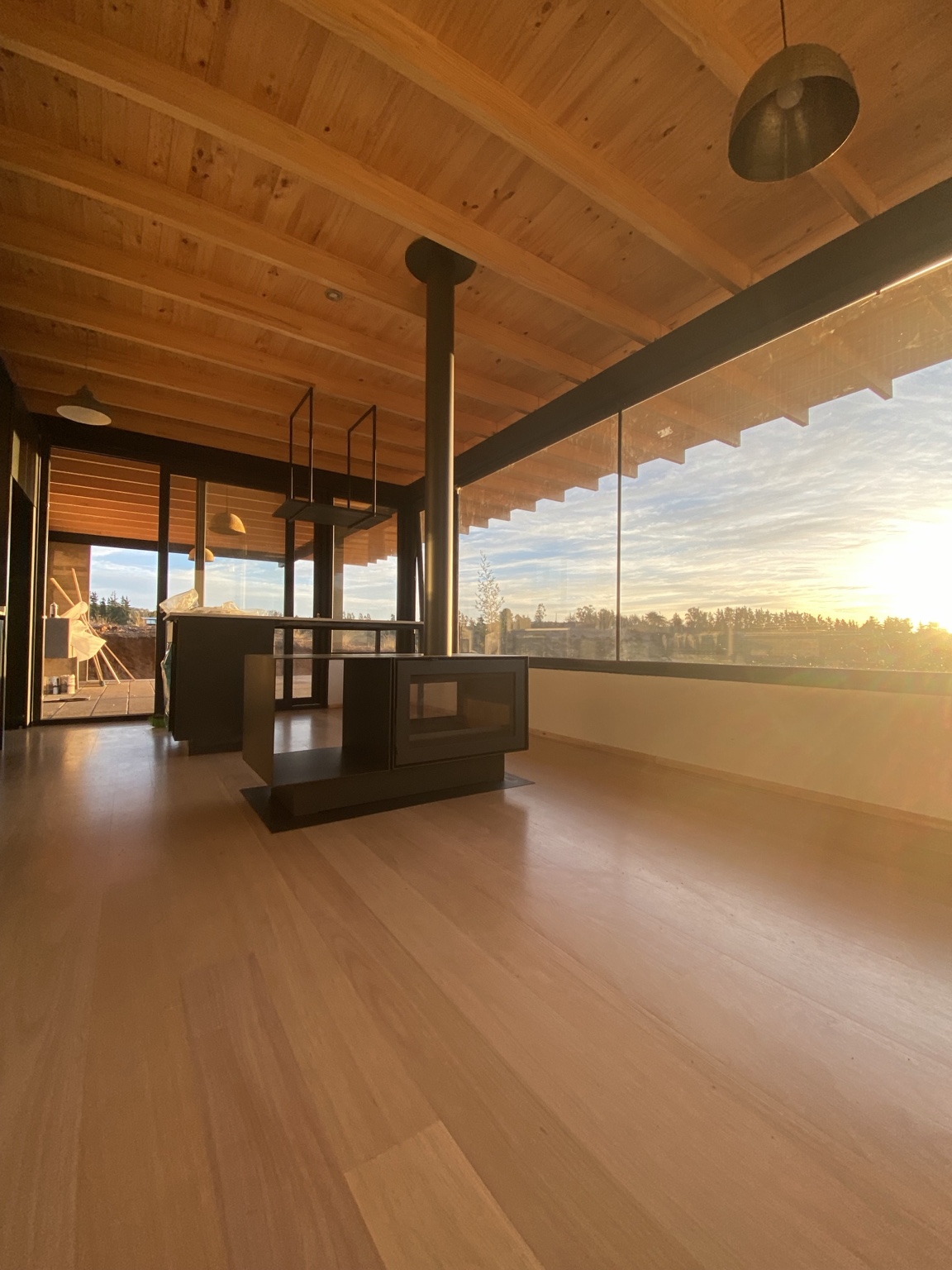 Vista completa de chimenea con doble vidrio, leñero lateral y tubería negra